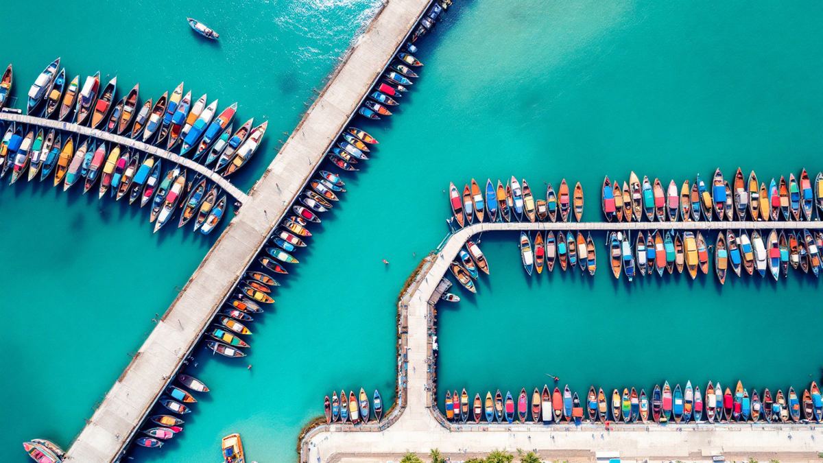 Aerial view of colourful wooden fishing boats moored in rows in a turquoise Bali harbour