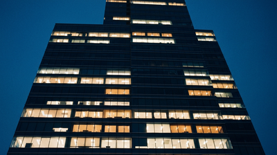 An office tower at night with a scattered handful of floors still lit