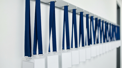 Row of blank credential lanyards and ID badges on wall hooks