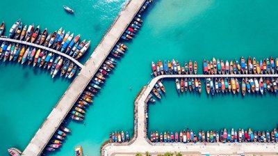 Aerial view of colourful wooden fishing boats moored in rows in a turquoise Bali harbour