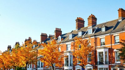 Red brick terraced houses behind golden autumn trees on a British street